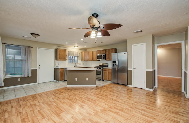 10829 E Linwood Dr, La Porte, TX 77571 - kitchen with stainless steel appliances, light wood-style flooring, a ceiling fan, light countertops, and a center island
