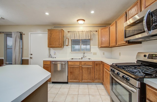 10829 E Linwood Dr, La Porte, TX 77571 - kitchen featuring stainless steel appliances, a sink, light tile patterned floors, brown cabinets, and light countertops