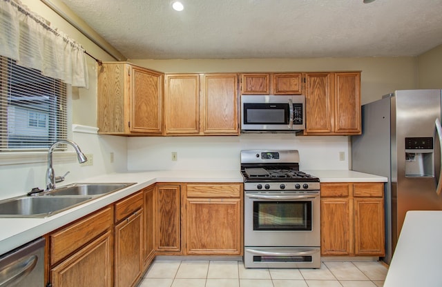 10829 E Linwood Dr, La Porte, TX 77571 - kitchen with stainless steel appliances, a sink, light countertops, light tile patterned floors, and a textured ceiling