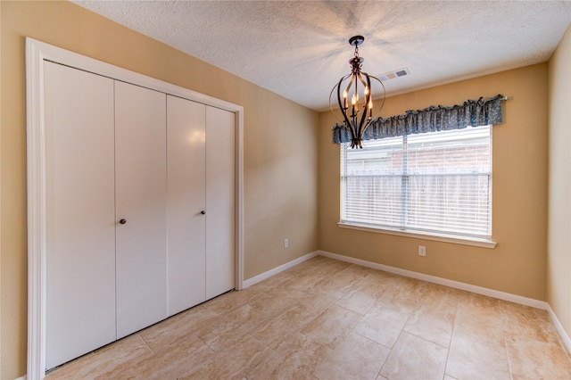 24014 Whitefield Ln, Katy, TX 77493 - unfurnished bedroom with a chandelier, a closet, a textured ceiling, baseboards, and light tile patterned floors