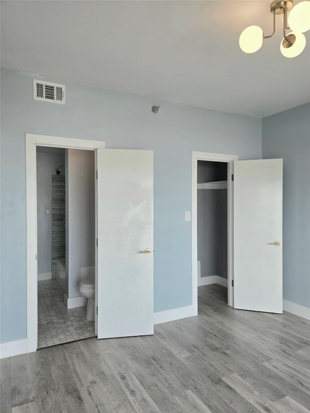 7700 Seawall Blvd Unit 409, Galveston, TX 77551 - unfurnished bedroom featuring wood finished floors, baseboards, a chandelier, and connected bathroom