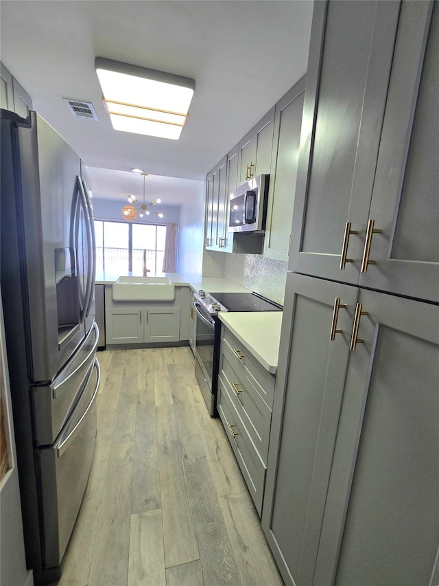 7700 Seawall Blvd Unit 409, Galveston, TX 77551 - kitchen with stainless steel appliances, gray cabinets, light wood-type flooring, and light countertops