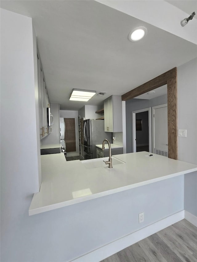 7700 Seawall Blvd Unit 409, Galveston, TX 77551 - kitchen featuring freestanding refrigerator, wood finished floors, a peninsula, light countertops, and a sink