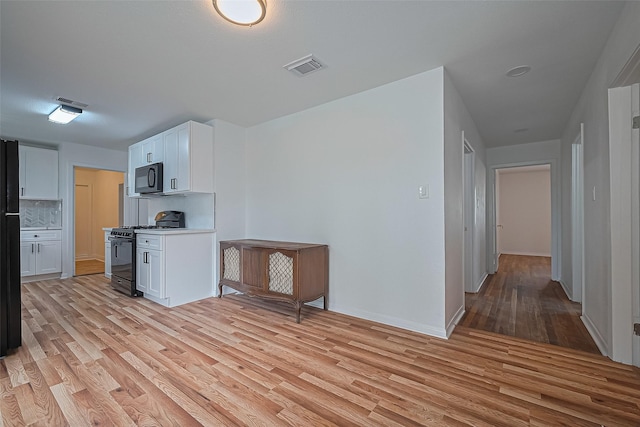 1029 Dolly Wright St, Houston, TX 77088 - kitchen with black appliances, light wood finished floors, white cabinetry, decorative backsplash, and light countertops
