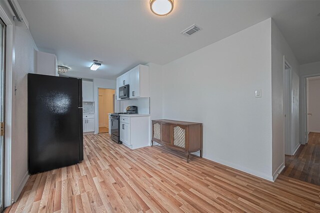 1029 Dolly Wright St, Houston, TX 77088 - kitchen featuring black appliances, light wood-style flooring, white cabinetry, light countertops, and baseboards