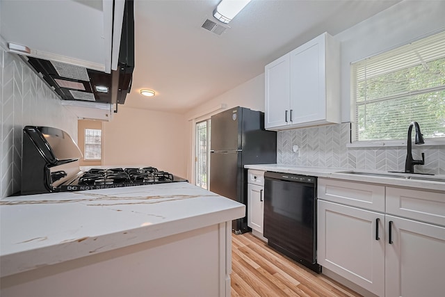 1029 Dolly Wright St, Houston, TX 77088 - kitchen with black appliances, a sink, white cabinetry, exhaust hood, and light wood-style flooring