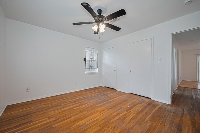 1029 Dolly Wright St, Houston, TX 77088 - unfurnished bedroom featuring wood finished floors, baseboards, ceiling fan, and two closets