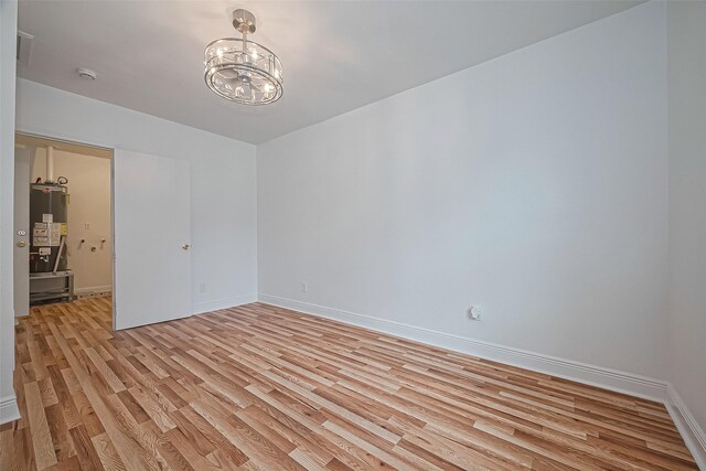 1029 Dolly Wright St, Houston, TX 77088 - empty room featuring light wood-style flooring, a chandelier, baseboards, water heater, and a smoke detector