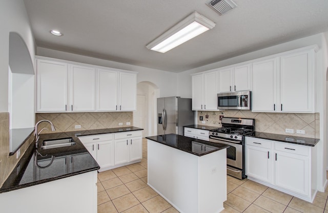 6018 Lamb Crk, Missouri City, TX 77459 - kitchen with appliances with stainless steel finishes, a sink, arched walkways, decorative backsplash, and dark stone counters