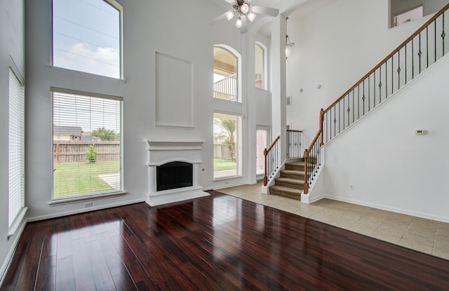 6018 Lamb Crk, Missouri City, TX 77459 - unfurnished living room with a high ceiling, stairs, ceiling fan, hardwood / wood-style flooring, and a fireplace with raised hearth