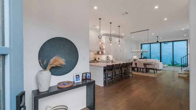 1410 Indiana St, Houston, TX 77006 - kitchen with dark wood-style flooring, recessed lighting, a kitchen bar, white cabinetry, and a large island with sink