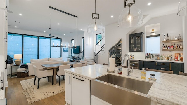 1410 Indiana St, Houston, TX 77006 - kitchen featuring a sink, hanging light fixtures, open floor plan, light wood-style flooring, and light stone counters