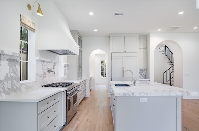 1732 Libbey Dr, Houston, TX 77018 - kitchen featuring high quality appliances, arched walkways, custom exhaust hood, a sink, and a kitchen island with sink