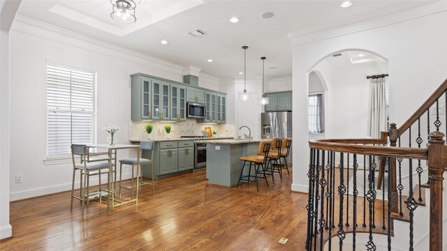 1415 W 21st St Unit A, Houston, TX 77008 - kitchen featuring appliances with stainless steel finishes, wood finished floors, decorative backsplash, a kitchen bar, and recessed lighting