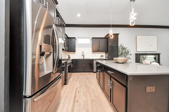 1544 W 23rd St Unit B, Houston, TX 77008 - kitchen with stainless steel appliances, ornamental molding, a sink, a kitchen island, and light wood-type flooring