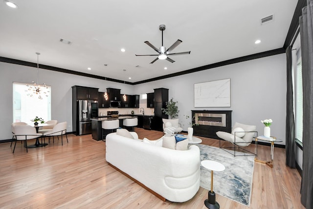 1544 W 23rd St Unit B, Houston, TX 77008 - living room with crown molding, ceiling fan, a chandelier, light wood finished floors, and a glass covered fireplace
