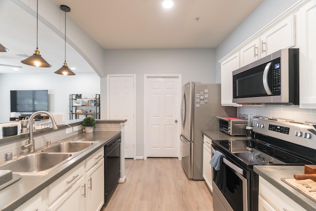 6607 Lake Woodlands Dr Unit 312, The Woodlands, TX 77382 - kitchen featuring appliances with stainless steel finishes, a sink, backsplash, white cabinetry, and light wood-style floors