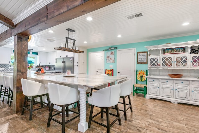 1310 Hickory Ln, Houston, TX 77339 - kitchen with high quality fridge, a breakfast bar, white cabinetry, light stone counters, and recessed lighting