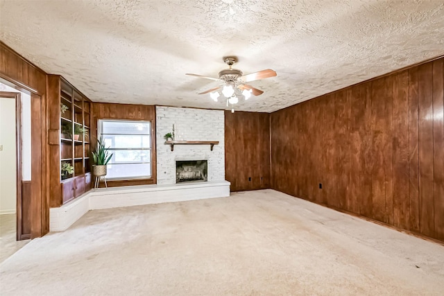 15419 Diana Ln, Houston, TX 77062 - unfurnished living room featuring wooden walls, a ceiling fan, a fireplace, a textured ceiling, and carpet floors