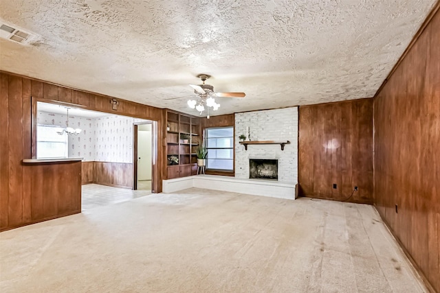 15419 Diana Ln, Houston, TX 77062 - unfurnished living room featuring wood walls, ceiling fan, a fireplace, a textured ceiling, and plenty of natural light