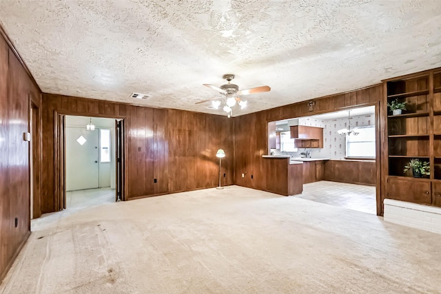 15419 Diana Ln, Houston, TX 77062 - unfurnished living room featuring wood walls, a ceiling fan, a textured ceiling, and light colored carpet
