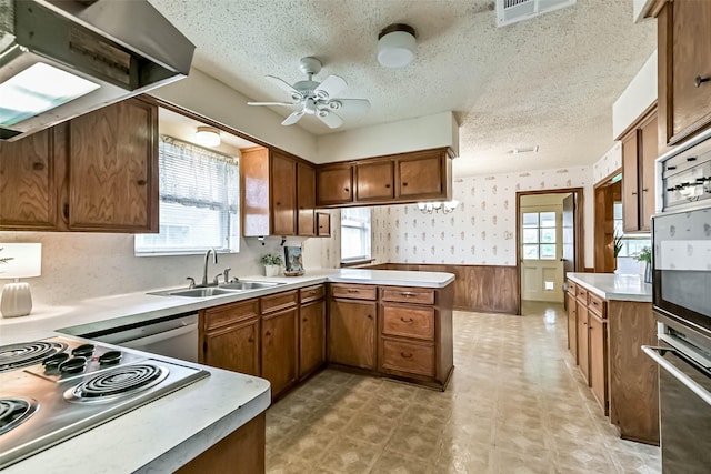 15419 Diana Ln, Houston, TX 77062 - kitchen with exhaust hood, a sink, wainscoting, a textured ceiling, and brown cabinetry