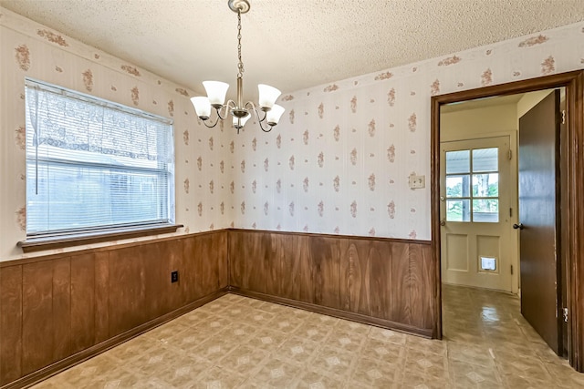 15419 Diana Ln, Houston, TX 77062 - unfurnished dining area featuring a textured ceiling, wallpapered walls, a wainscoted wall, and a chandelier