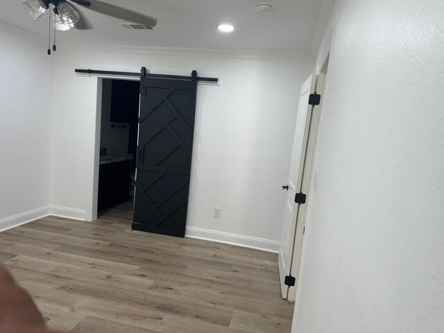 4120 Buffalo St, Beaumont, TX 77703 - unfurnished bedroom with crown molding, a barn door, baseboards, wood finished floors, and recessed lighting