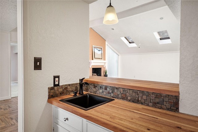 707 Center Hill Dr, Houston, TX 77079 - kitchen with a sink, vaulted ceiling, butcher block countertops, white cabinets, and a textured wall