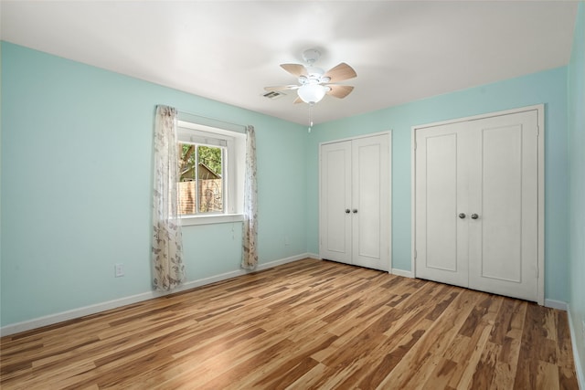 707 Center Hill Dr, Houston, TX 77079 - unfurnished bedroom with wood finished floors, baseboards, two closets, and a ceiling fan