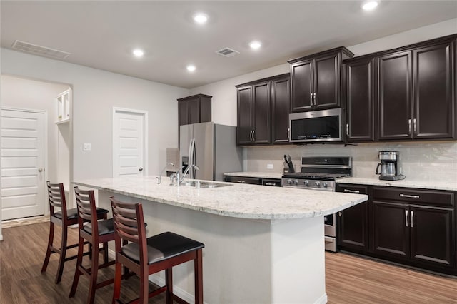 5514 Oriente Ln, Houston, TX 77023 - kitchen featuring appliances with stainless steel finishes, light wood-style flooring, a breakfast bar, backsplash, and recessed lighting