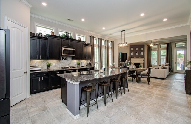 3111 Jane Way, Richmond, TX 77406 - kitchen featuring stainless steel appliances, a kitchen breakfast bar, ornamental molding, backsplash, and dark stone counters