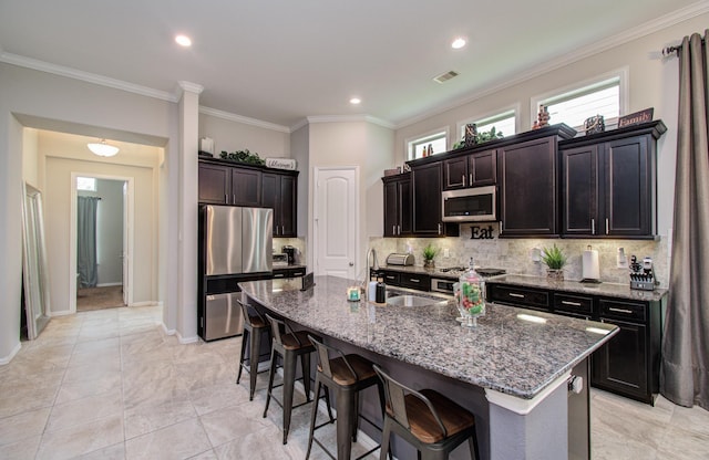 3111 Jane Way, Richmond, TX 77406 - kitchen featuring appliances with stainless steel finishes, a sink, a breakfast bar area, dark stone counters, and ornamental molding