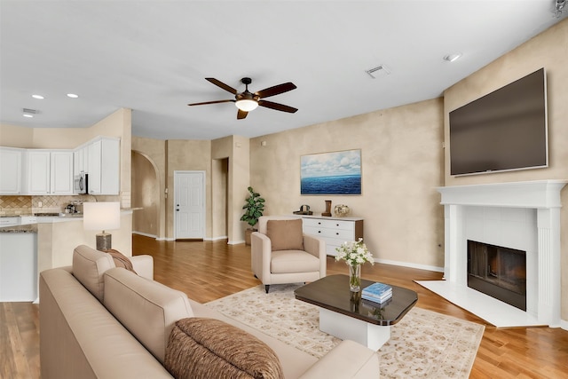 20434 Willow Trace Dr, Cypress, TX 77433 - living area featuring ceiling fan, wood finished floors, a tiled fireplace, baseboards, and arched walkways