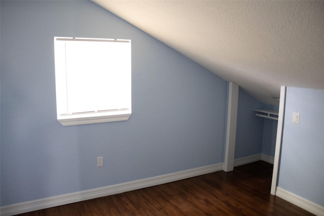7301 Ave K, Houston, TX 77011 - bonus room featuring vaulted ceiling, dark wood-style floors, baseboards, and a textured ceiling