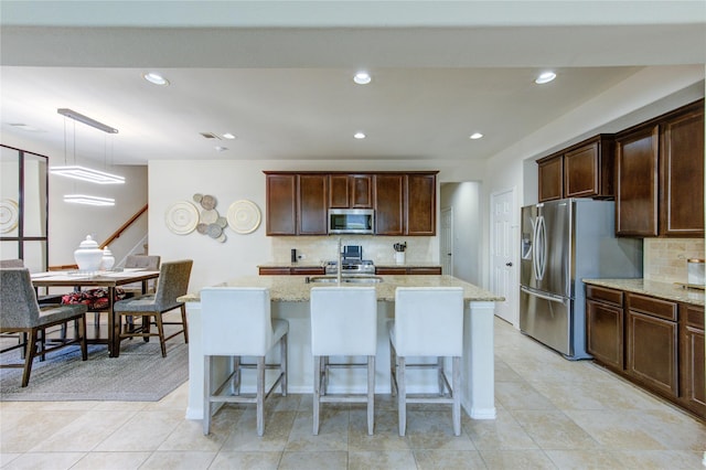 223 Summer Gate Ct, Rosenberg, TX 77469 - kitchen with appliances with stainless steel finishes, light stone countertops, tasteful backsplash, an island with sink, and recessed lighting