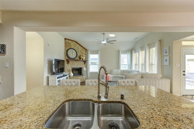 223 Summer Gate Ct, Rosenberg, TX 77469 - kitchen featuring a sink, lofted ceiling, light stone counters, a ceiling fan, and a stone fireplace