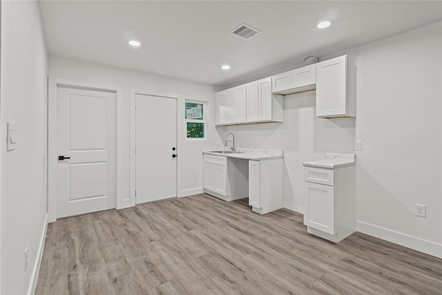 805 19th Ave N, Texas City, TX 77590 - kitchen with a sink, white cabinets, light wood-style flooring, baseboards, and light countertops