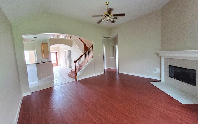 2707 Sun Beam Ct, Pearland, TX 77584 - unfurnished living room featuring a ceiling fan, wood finished floors, stairs, arched walkways, and a tiled fireplace