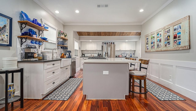 405 N Grace St N, Houston, TX 77003 - kitchen featuring stainless steel appliances, a sink, crown molding, dark wood-type flooring, and white cabinets