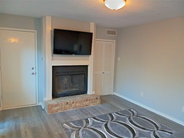 800 Country Place Dr Unit 909, Houston, TX 77079 - unfurnished living room with a brick fireplace, wood finished floors, baseboards, and a textured ceiling