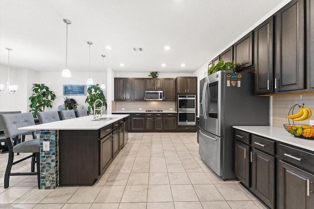 1164 Clonmore Ct, Conroe, TX 77304 - kitchen featuring stainless steel appliances, a sink, backsplash, dark brown cabinetry, and light countertops