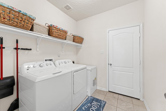 1164 Clonmore Ct, Conroe, TX 77304 - laundry area with washing machine and clothes dryer, light tile patterned floors, baseboards, and a textured ceiling
