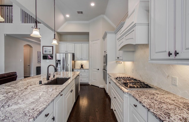 31297 New Forest Park Ln, Spring, TX 77386 - kitchen with appliances with stainless steel finishes, arched walkways, white cabinets, light stone countertops, and ornamental molding