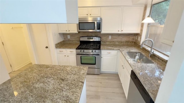1419 Valley Landing Dr, Katy, TX 77450 - kitchen with appliances with stainless steel finishes, a sink, white cabinetry, light stone counters, and light wood finished floors