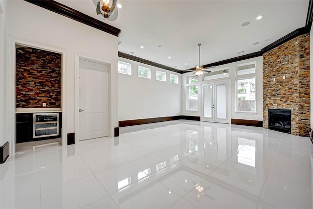 825 W 16th St Unit A, Houston, TX 77008 - unfurnished living room featuring wine cooler, ornamental molding, a stone fireplace, a ceiling fan, and light tile patterned floors