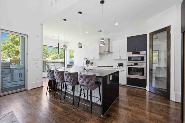 2310 Althea Dr, Houston, TX 77018 - kitchen with wall chimney range hood, gas cooktop, a kitchen breakfast bar, a kitchen island with sink, and dark wood finished floors