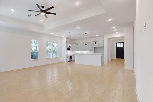 117 Keaau Ct, Bastrop, TX 78602 - unfurnished living room featuring recessed lighting, baseboards, a ceiling fan, a raised ceiling, and light wood-type flooring