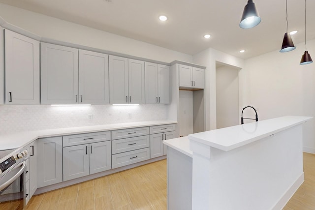 117 Keaau Ct, Bastrop, TX 78602 - kitchen featuring decorative backsplash, hanging light fixtures, stainless steel electric range, light countertops, and a kitchen island with sink