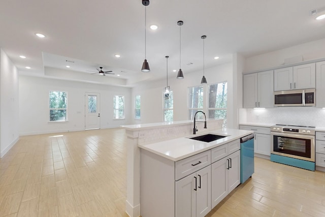 117 Keaau Ct, Bastrop, TX 78602 - kitchen featuring appliances with stainless steel finishes, a sink, light countertops, decorative backsplash, and a ceiling fan